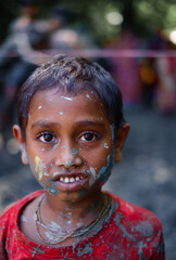 South asian hindu religious little boy enjoying holi festival,the occasion of colour , abir or gulal on face in bijoya dashami of durga puja
