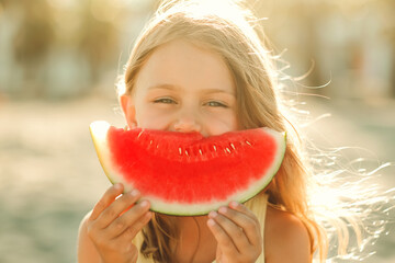 Portrait happy excited funny child little girl eat piece of juice watermelon on beach. Concept of...