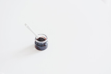 Jar with black currant jam on white wooden table