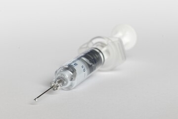 blurred syringe with droplet of fluid on needle