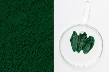 Spirulina face cream or mask in a Petri dish. Spreading spatula. Spirulina powder close up.