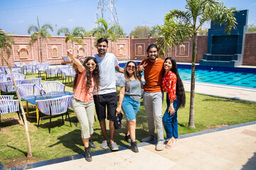 Group of young indian friends having fun standing at resort in hot sunny day. Summer holiday and...