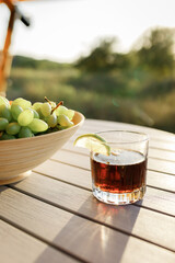 Glass of cocktail with rum and cola is standing on the table outside on nature background