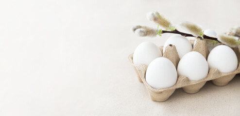 Easter holiday. White eggs in an eco box - a willow branch on top, background - natural linen fabric. 