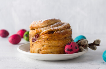 Easter cake Kraffin with nuts and dried fruits, sprinkled with powdered sugar, decorated with a painted egg and willow branches on a light blue background