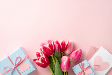 Mother's Day atmosphere concept. Top view photo of bunch of pink tulips blue gift boxes envelope and letter with heart on isolated pastel pink background with empty space