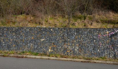 construction of a gabion retaining wall, as part of the house fencing. workers put geotextiles and...