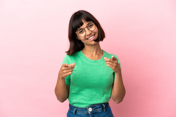 Young mixed race woman isolated on pink background pointing front with happy expression