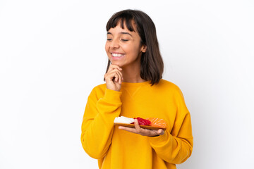 Young mixed race woman holding sashimi isolated on white background looking to the side and smiling