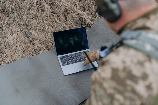 A soldier works on his laptop. A military scout in the field works by coordinates