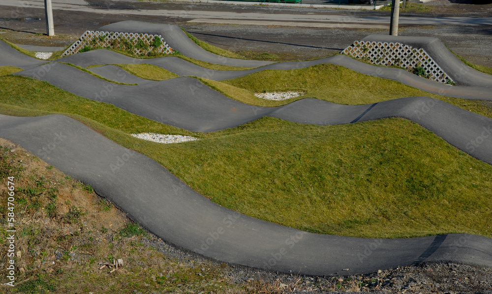 Wall mural bike path in the car park Pumping (moving up and down) is used instead of pedaling and bouncing to move bicycles, scooters, skateboards and inline skates along the modular pumptrack track