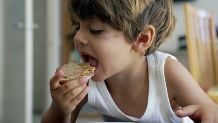 Portrait of a young boy snacking peanut butter bread. Closeup child face eating snack food toast