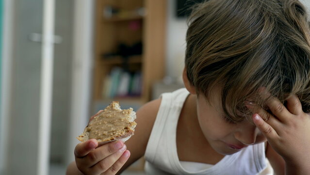 Portrait of a young boy snacking peanut butter bread. Closeup child face eating snack food toast