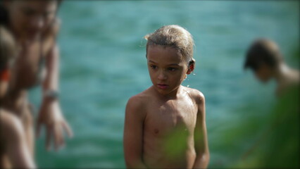 Pensive child standing outside after bathing at beach. Thoughtful small boy stands outdoors. Wet kid © Marco