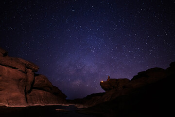 Traveler hiker who sitting top of mountain with lighting beautiful night starry sky milky way is...