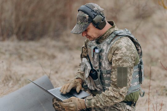 A soldier works on his laptop. A military scout in the field works by coordinates - Powered by Adobe