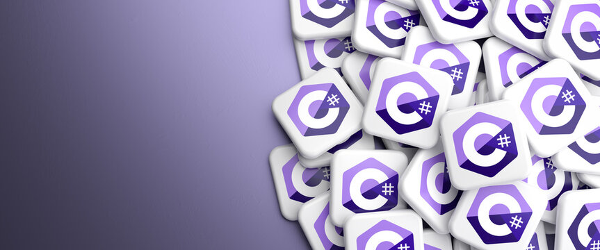 Logos of the programming language C# (C sharp) on a heap on a table. Web banner format, copy space
