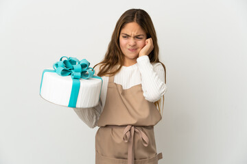 Little girl holding a big cake over isolated white background frustrated and covering ears