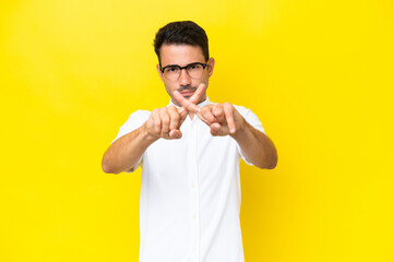 Young handsome man over isolated yellow background making stop gesture with her hand to stop an act