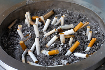 Cigarettes and ash on dirty sand in trash tray