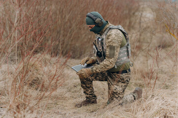 military man stands in camouflage and works with a laptop. military intelligence