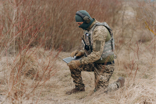 military man stands in camouflage and works with a laptop. military intelligence