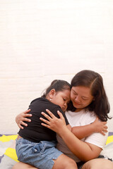 Fototapeta premium Sad asian girl hugging his mother on the bed at home