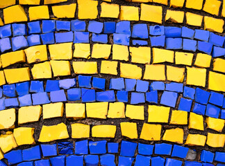 Detail of a beautiful bright multi-colored mosaic of the Soviet era. Abstract texture background from decorative geometric stones. Ukraine flag colors