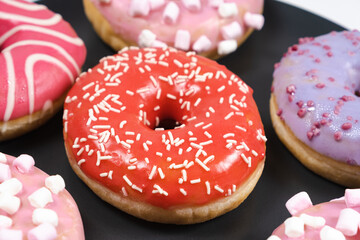 Donuts with red and pink glaze. Lots of donuts, sweet and delicious food