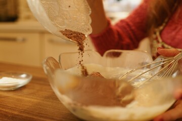 Close-up view of adding cocoa powder to the pastry dough. The moment of spilling the cocoa powder while making the cookie dough.