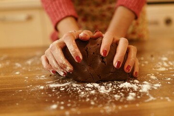 Close-up shot of a woman kneading dough in the kitchen with only her hands visible.