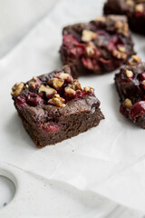 Chocolate brownie with cherries and berries nuts on top on white background close up selective focus