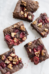 Chocolate brownie with cherries and berries nuts on top on white background close up selective focus