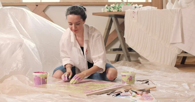 Front view of woman artist painting with hands on canvas in art studio and smiling. Art creativity concept.