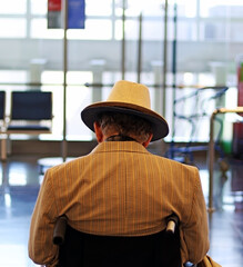 Adult male in suit and yellow hat in wheelchair