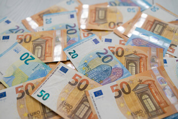 Euro money banknotes. Bundle of 50 and 20 euro bills on white wooden background. Flat lay of euros banknotes