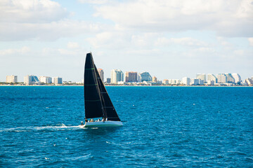 A fully crewed sports sailing yacht sailing off the coast of Fort Lauderdale, Florida.
