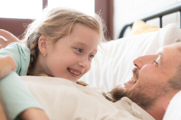 A father enjoys talking with his daughter in his bedroom. before saying goodbye and sending her daughter to bed