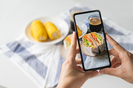 Female taking photo of healthy freshly made sandwiches with smart phone to share on social media