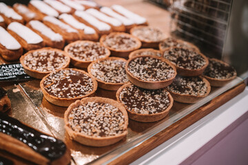 a display case filled with lots of different types of cakes and pies on display in a bakery or deli or bakery shop front view of cakes and frosted with frosting on the shelves. Selective Focus. High