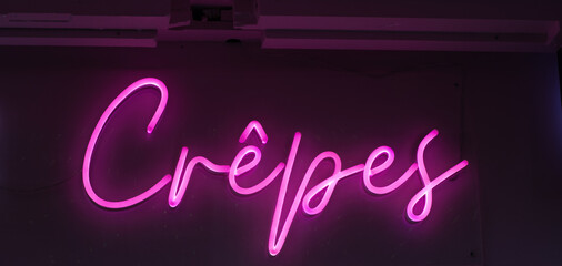 pink neon sign crepes on a cafe