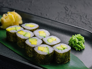 Maki sushi roll with avocado on black plate