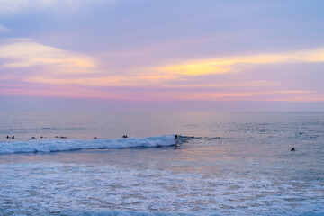 Obraz premium Surfers catch waves, surfing at sunset. Bali.