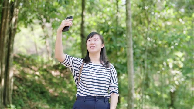 Woman visiting the mangrove forest taking photos and video calling