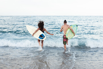 Surfers running into water.