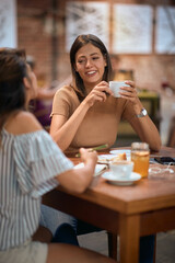 Girlfriends having coffee together. Young women enjoying their time in cafe, feeling joyful.