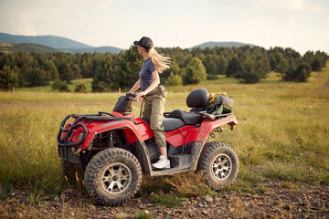 Fototapeta na wymiar A young girl is enjoying the scenery while riding a quad in the nature. Riding, nature, activity