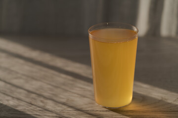 Ginger beer in tumbler glass on white oak table wuth sunlight