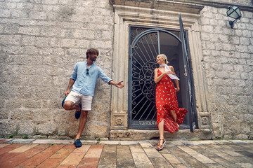 Couple in front of old building. Man waiting for woman leaving building. Young stylish fashionable people. Date, honeymoon, love, holiday concept.