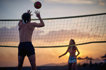 Man hitting volley ball. Group of friends playing at the beach. Sport, recreation, fun, togetherness, lifestyle concept.